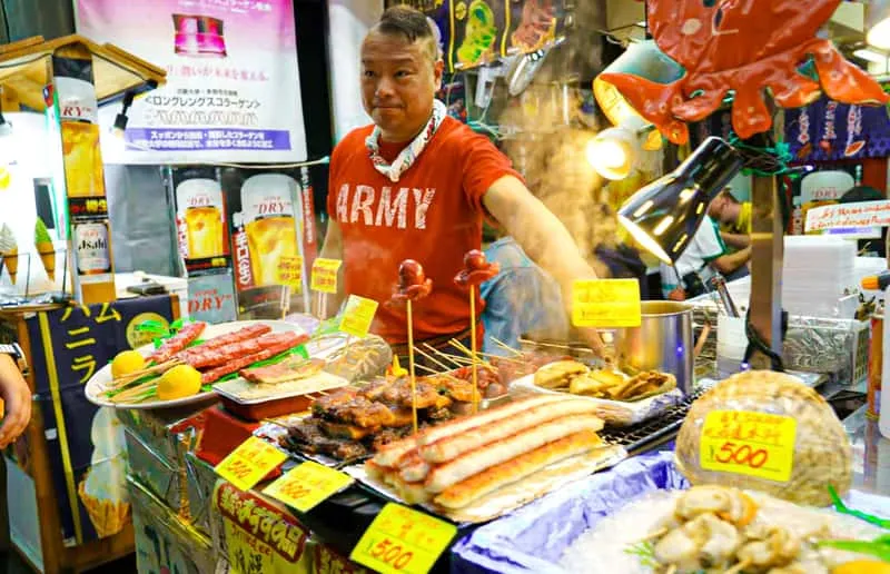 Guide leading tastings past food stalls at Nishiki Market on a kyoto food tour through Gion, Kyoto, Japan